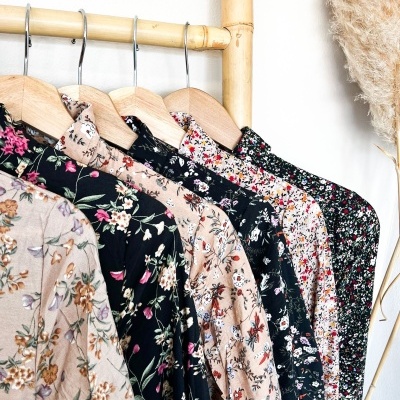 Vestidos florais pendurados em cabides de madeira