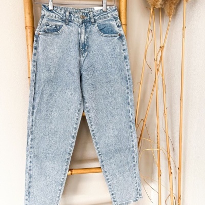 Calças de ganga azul claro penduradas numa estrutura de bambu num cenário interno