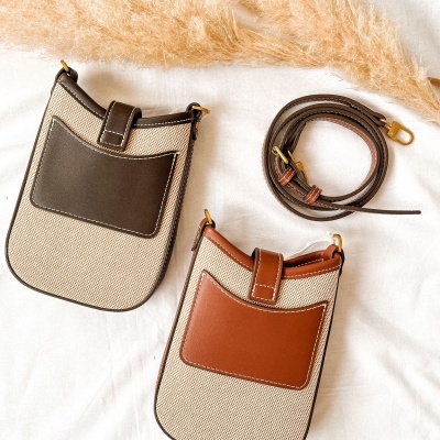Dois sacos tipo bolsa bege com bolsos frontais em couro castanho e uma alça de couro castanho.
