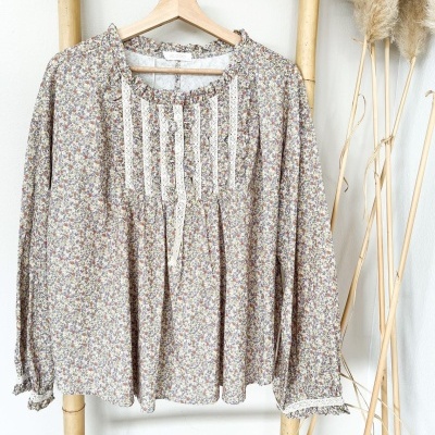 Blusa floral com renda pendurada em cabide de madeira numa escada de bambu