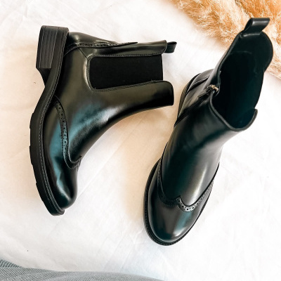 Par de botins pretos em couro com salto baixo e detalhe elástico lateral