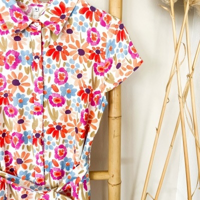 Vestido de tecido com padrão floral colorido pendurado num cabide de madeira