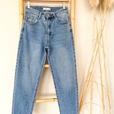 Calças de ganga azuis claras penduradas numa estrutura de bambu.