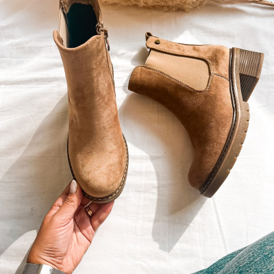 Botas castanhas de camurça com salto médio e elástico lateral sobre tecido branco