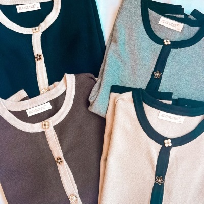Cardigans dobrados em diferentes cores com botões florais e etiquetas BLUCOTRE
