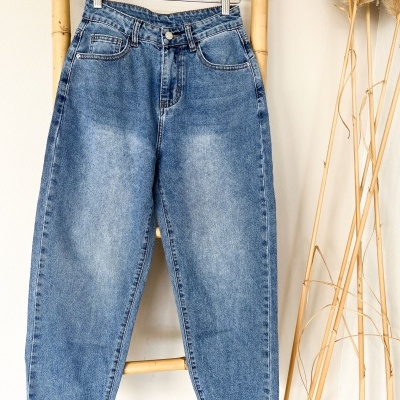 Calças de ganga azuis com bainha virada penduradas num suporte de bambu