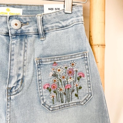 Calças de ganga claras com bordado floral no bolso