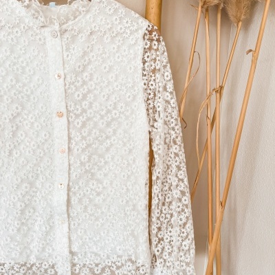 Camisa branca de renda floral pendurada em cabide de madeira