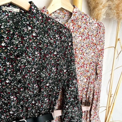 Vestidos florais com cintos pendurados em cabides de madeira