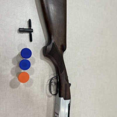 Espingarda de madeira e metal com acessórios coloridos sobre superfície clara