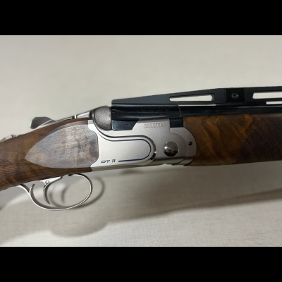 Espingarda Beretta DT11 com punho em madeira castanha e armação metálica prateada
