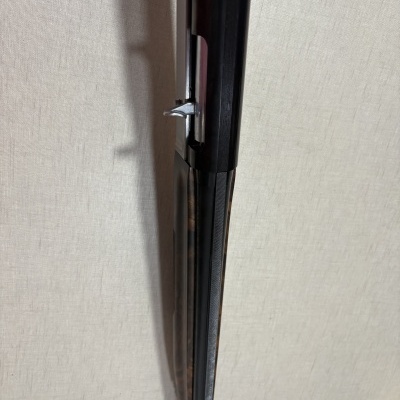 Parte superior de espingarda de canos paralelos em metal preto e madeira.