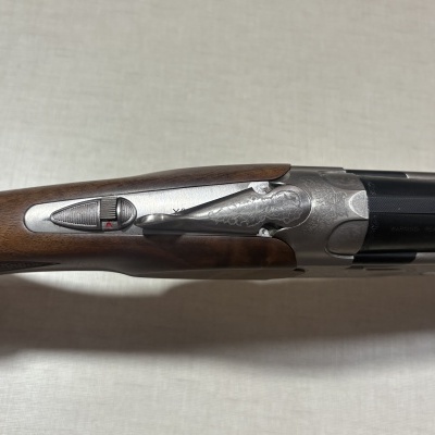 Espingarda de canos duplos com coronha em madeira escura e detalhes em metal prateado