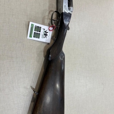 Espingarda de caça com coronha em madeira e cano metalizado sobre superfície bege