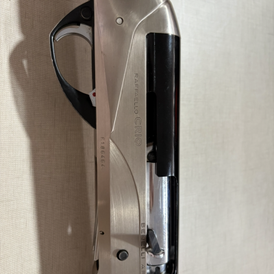 Espingarda metálica prateada e preta com empunhadura de madeira e gravações visíveis