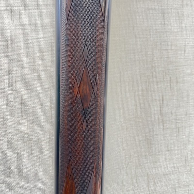 Objeto de madeira escura com padrão gravado sobre fundo bege claro