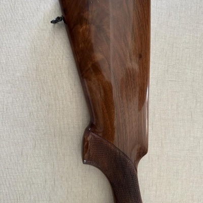 Coronha de espingarda em madeira polida castanha com punho quadriculado e ponta vermelha