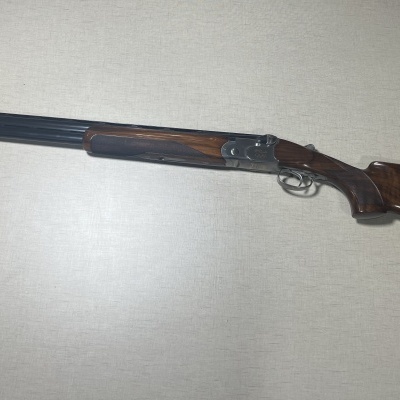 Espingarda de canos duplos em madeira e metal prateado sobre fundo claro