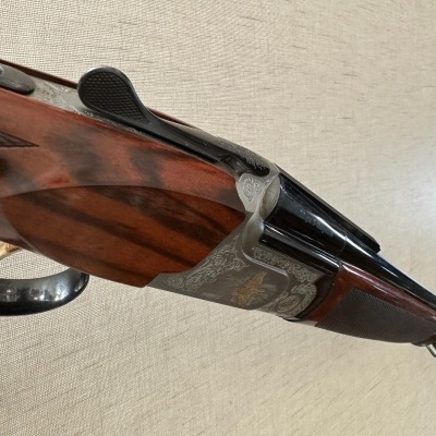 Espingarda de canos duplos com madeira vermelha polida e detalhes em metal cinzento gravado