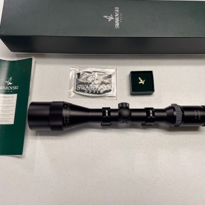 Conjunto de mira telescópica e acessórios da Swarovski sobre mesa branca