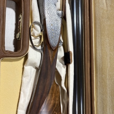 Espingarda de madeira e metal decorada numa caixa bege