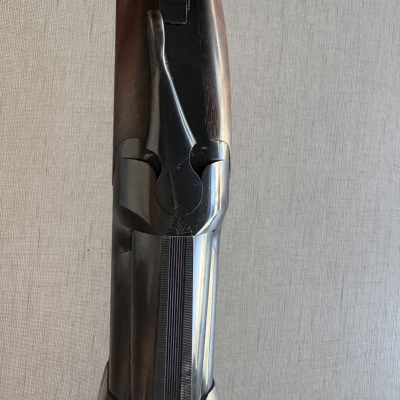 Espingarda de cano duplo em madeira castanha e metal polido sobre fundo cinzento