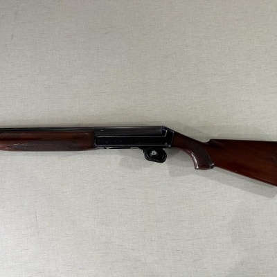 Espingarda em madeira castanha e metal preto fosco sobre fundo branco