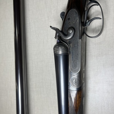 Espingarda de canos duplos em metal e madeira escura com detalhes gravados