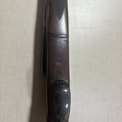 Espingarda de madeira escura com detalhes em metal e textura quadriculada