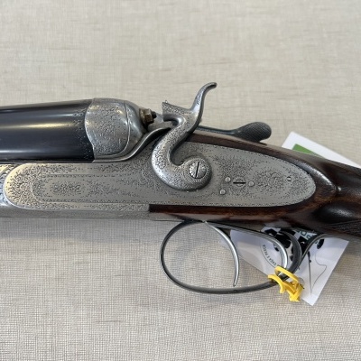 Espingarda de cano duplo com acabamento metálico gravado e empunhadura em madeira escura polida