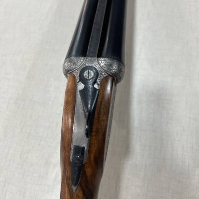 Espingarda de canos duplos com empunhadura em madeira e detalhes metálicos prateados