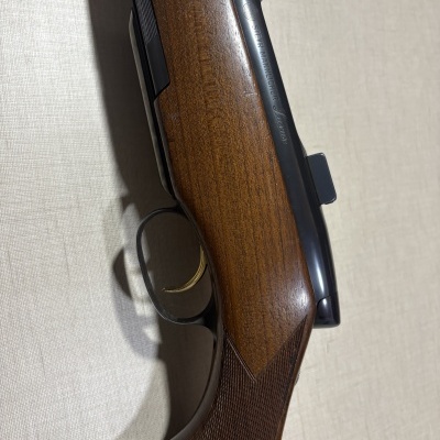 Espingarda de madeira com partes metálicas pretas e gatilho dourado