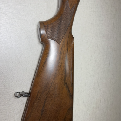 Coronha de espingarda de madeira castanha com peito texturizado e borracha preta.