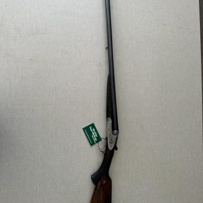 Espingarda de canos paralelos com coronha de madeira castanha e etiqueta verde