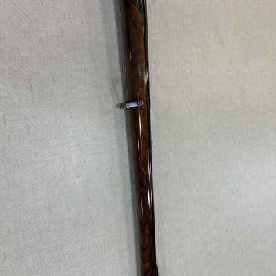 Arma longa de madeira escura com detalhes metálicos