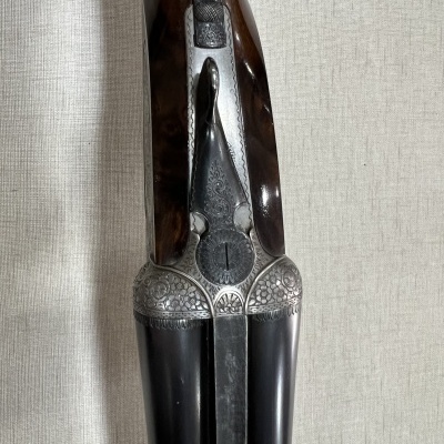 Detalhe de espingarda dupla com gravações florais e cabo em madeira castanha