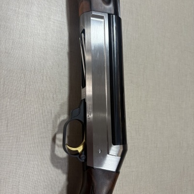 Espingarda com madeira castanha, metal prateado e preto sobre fundo bege