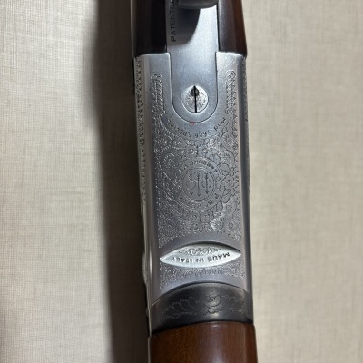 Parte superior de arma de fogo com metal prateado gravado, texto MADE IN ITALY, Mod. 686 SPECIAL, PATENTED e cabo de madeira castanha