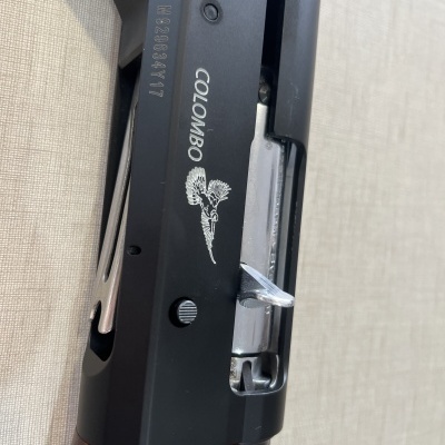 Arma de fogo preta com detalhes em madeira e marca COLOMBO