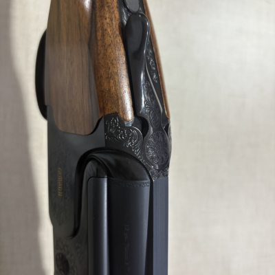 Espingarda de caça em madeira e metal preto com detalhes gravados