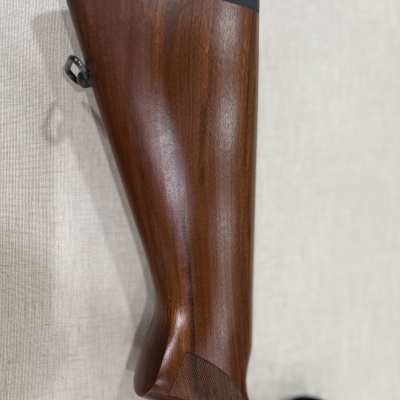 Cano de arma de madeira polida castanho com borracha preta na extremidade superior.