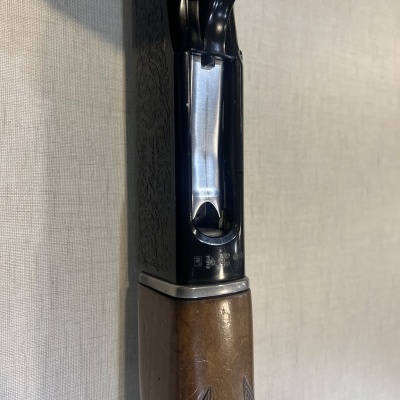 Parte superior de arma de caça em madeira e metal contra fundo cinzento