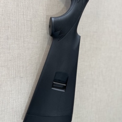 Coronha preta de espingarda com textura antiderrapante contra parede bege