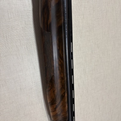 Metade de uma espingarda com punho de madeira castanha e cano preto