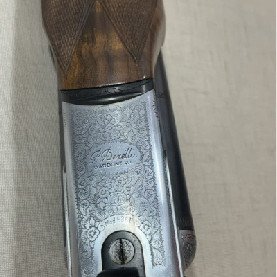 Parte de uma arma com gravuras e texto gravado em metal prateado