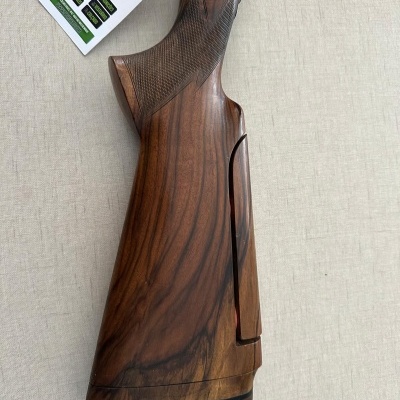 Parte traseira de arma de caça em madeira castanha escura com etiqueta pendurada