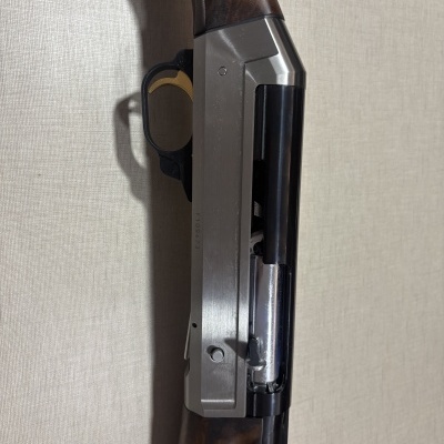 Espingarda com madeira escura e acabamento metálico prateado e preto