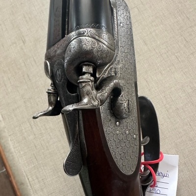 Espingarda de cano duplo com cabo em madeira e detalhes metálicos gravados