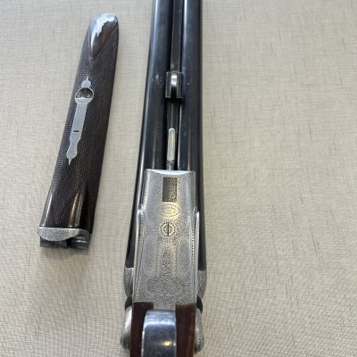 Espingarda de canos duplos com acabamento em metal gravado e empunhadura em madeira escura