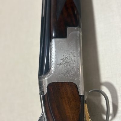Espingarda de caça com coronha em madeira escura e gravura metálica
